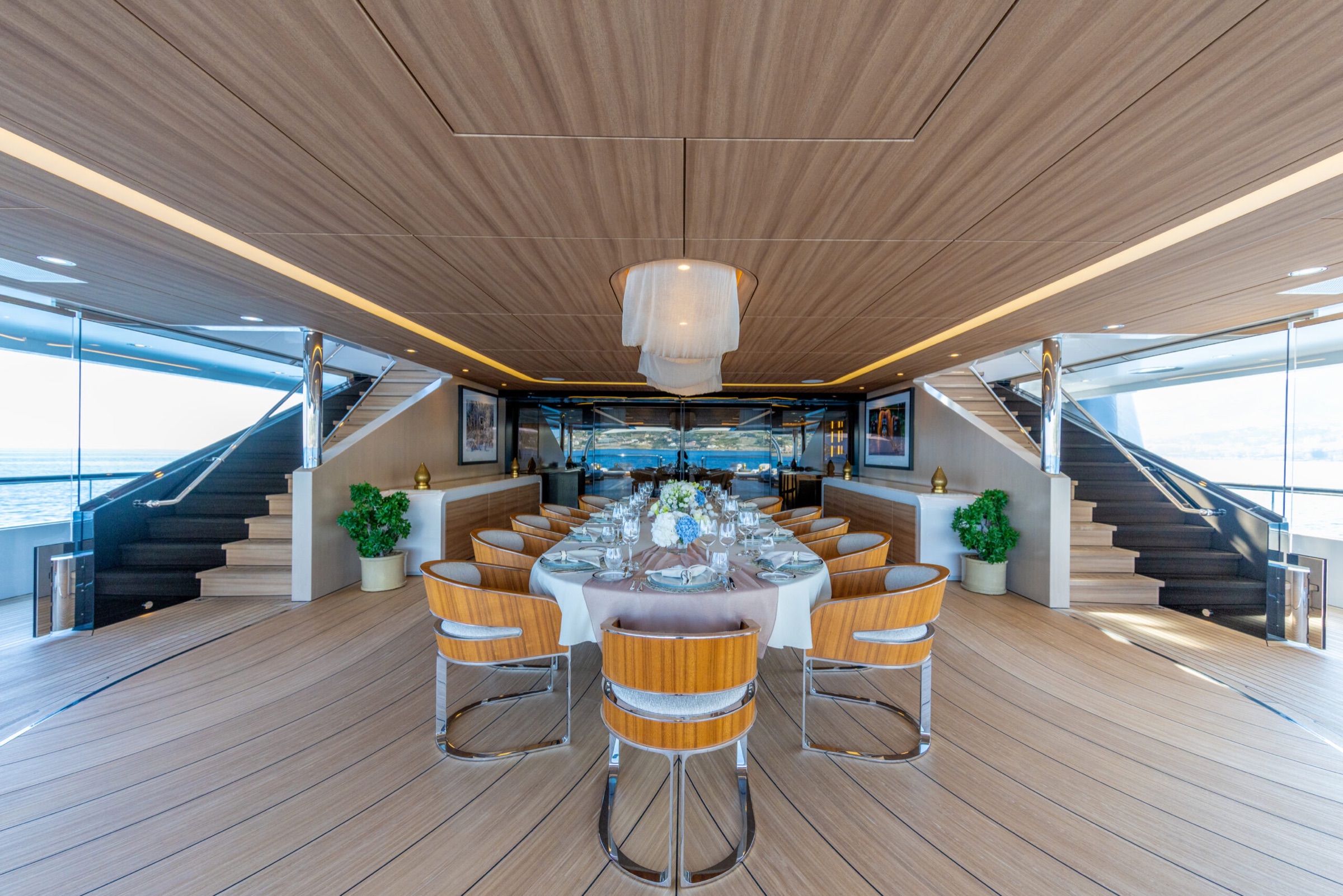 Dining table laid on a teak deck between twin staircases